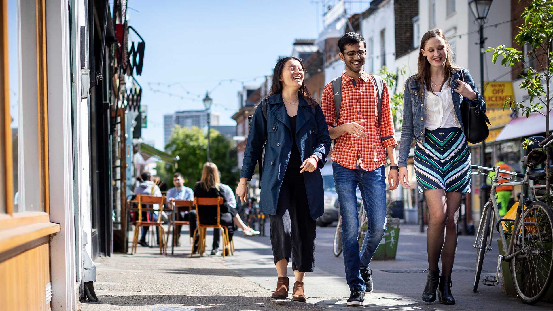 Three postgraduate students walking down Exmouth Market together on a sunny day