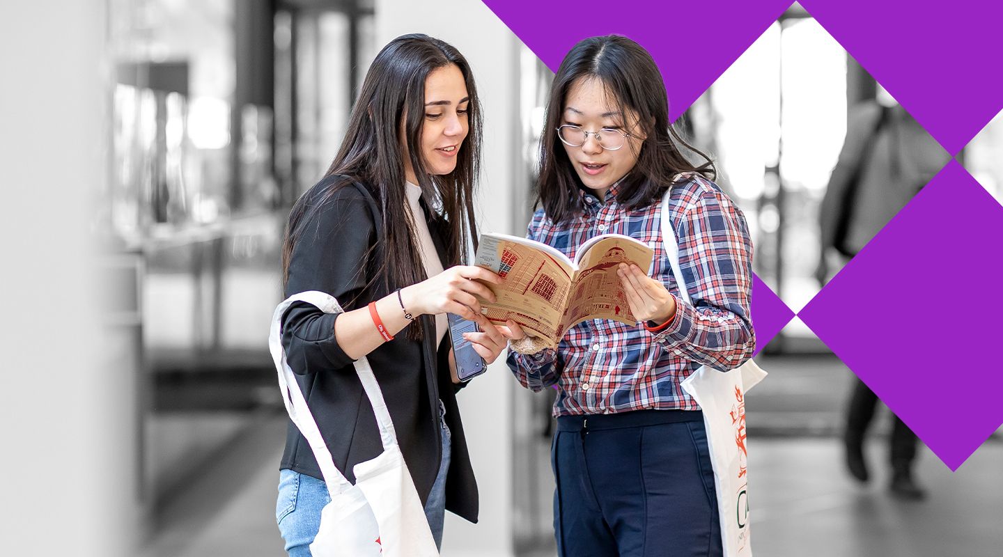 Two female students booking at a City prospectus